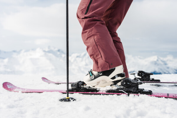 Eine Person klickt ihre Skischuhe in die Skier ein.