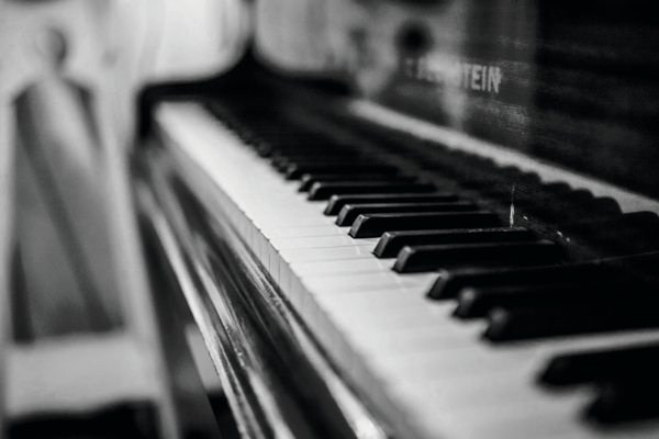Ein Klavier in schwarz weiß, von der Seite mit Fokus auf den Tasten fotografiert. 