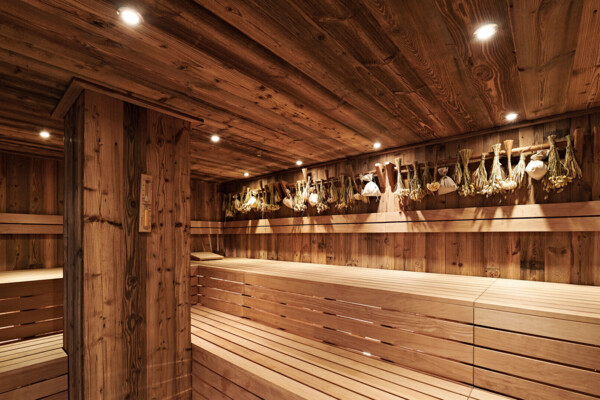 Das Innere einer traditionellen Holzsauna mit Bündeln von getrockneten Kräutern, die entlang der Wand hängen.